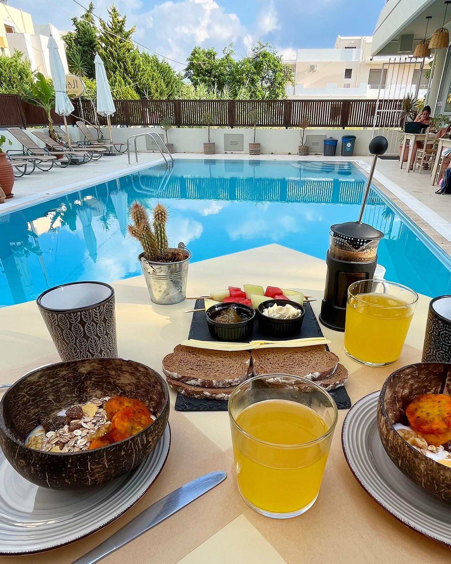 Breakfast by the poolside at Goji Vegan Hotel - yoghurt bowls, bread and cheese, French press coffee